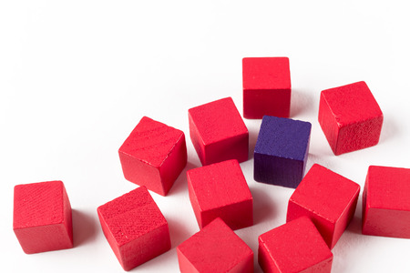 One blue wooden mini block among red blocks symbolizing exclusion, difference, or bullyingの写真素材