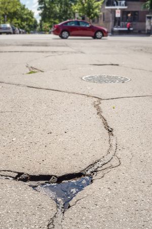 Large deep pothole  with traffic in the background in Montreal street, Canada.の写真素材