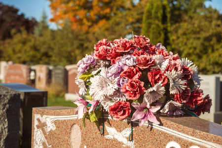 Flowers in a cemetery with headstones in the background at sunsetの写真素材