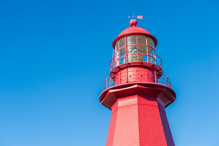 Top of a red lighthouse over blue sky in Gaspesie, Quebec (La Martre)の写真素材