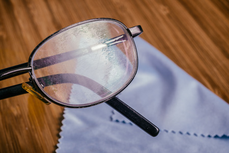 Old Eyeglass with many scratches and blue microfiber clothの写真素材