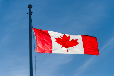 Canadian flag waving over blue sky in Victoria, Canada