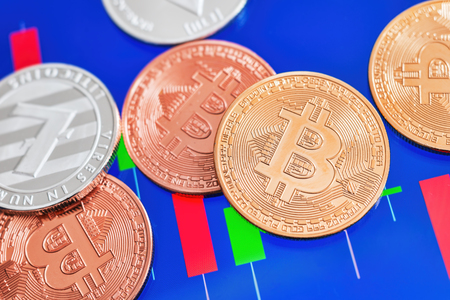 Cryptocurrency Bitcoin and Litecoin coins over tablet screen showing candlestick chart.の写真素材