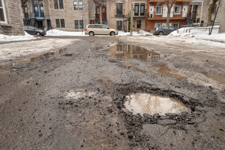 Montreal, CA - 13 March 2019: Large potholes in Montreal street, in Winterのeditorial素材