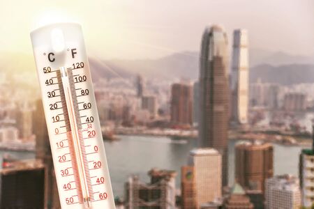 Thermometer in front of an urban skyline during heatwave