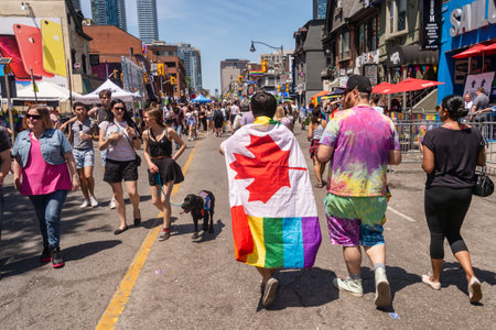 Toronto, CA - 23 June 2019: A man with a rainbow gay flag on his back is going to Toronto Gay Pride Parade.のeditorial素材