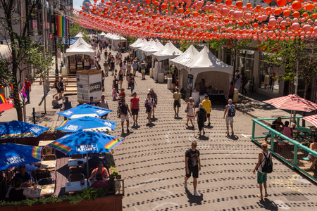 Montreal, CA - 1 July 2019: People walking below the Rainbow balls art installation "18 shades of gay" on Saint-Catherine Street in the Gay Villageのeditorial素材