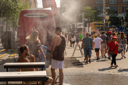 Montreal, CA - 27 July 2019: People walking under misting system to cool off (mist cooling system) during heatwave in Quartier des festivals.のeditorial素材