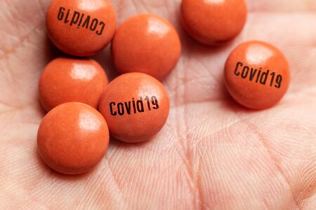 Illustration of a cure for Coronavirus Covid-19, man holding a pill with Covid-19 label.の写真素材