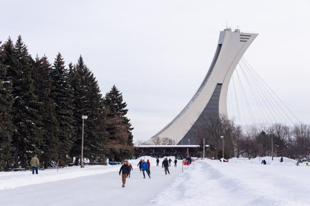 Montreal, CA - 15 February 2020: People  ice skating at the Park Maisonneuve ice rink with olympic Stadium Tower in background.のeditorial素材