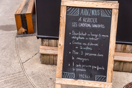 Montreal, CA - 16 May 2020: Guidelines and restrictions written in french on a chalkboard outside a store during the Covid-19 Pandemicのeditorial素材