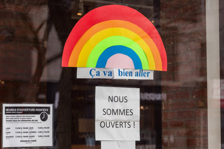 Montreal, CA - 16 May 2020: Ca va bien aller (Its going to be ok) message and Ouvert / Open sign on the door of a store during the Covid 19 pandemyのeditorial素材
