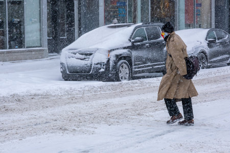Montreal, CA - 2 February 2021: Man with protective face mask walking on the street during heavy snowfallのeditorial素材