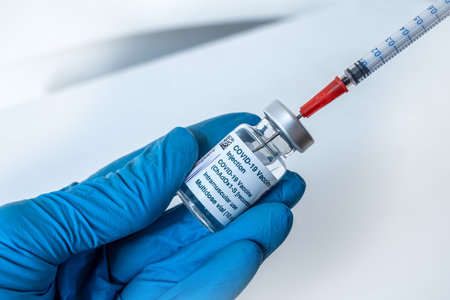 Montreal, CA - 4 March 2021: Hand in blue glove holding vial of Astrazeneca Covid-19 vaccineのeditorial素材