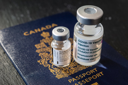 Montreal, CA - 8 March 2021: Vials of Astrazeneca and Pfizer Covid-19 vaccines over canadian passportのeditorial素材