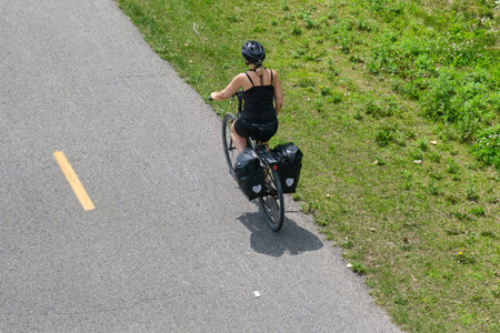 Montreal, CA - 4 July 2021: Woman riding bike on  Lachine Canalâ€™s bike path