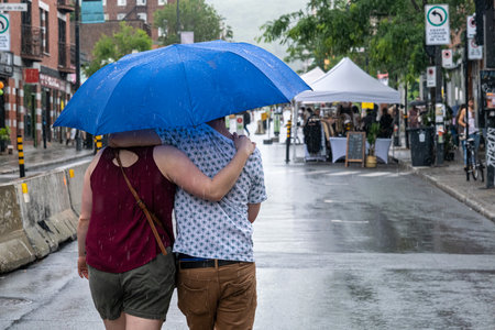 Montreal, CA - 12 June 2022: People on Mont-Royal Avenue holding umbrella during rain & stormのeditorial素材