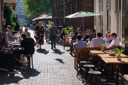 Amsterdam, The Netherlands - 22 June 2022: People eating at a restaurant on paved streetのeditorial素材