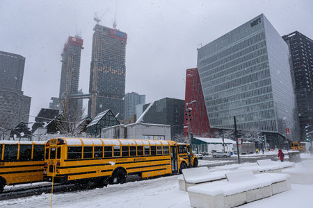 Montreal, CA - 16 November 2022: Yellow school buses parked in Montreal Downtown during snow storm