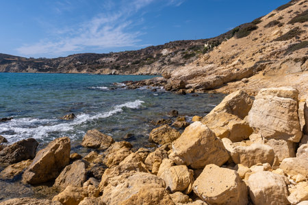 The rocky coast of Agios Sostis beach, where turquoise waters meet golden rocks
