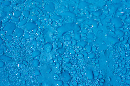 water drops of different sizes on a smooth blue surface in a drinking water pumping stationの写真素材