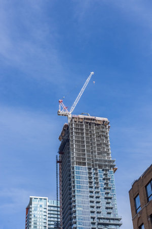 construction site with a white crane on top of an office or apartment tower in Toronto that has a glass frontの写真素材