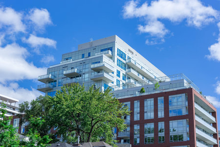 modern futuristic apartment complex in Toronto with trees ind the foreground and sky and clouds as backgroundの写真素材