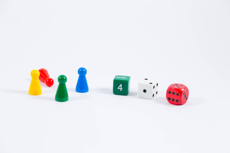 three green white and red colored dice showing four one six and four playing stones colored red green yellow and blue isolated on white backgroundの写真素材