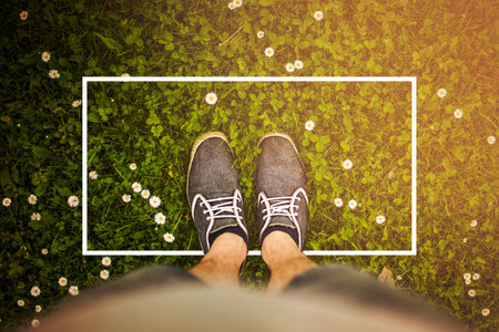 Summer field flowers grass with shoes and legs close up frame