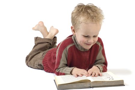 5 year old reading a book, isolated on white. Book is an old children's Bible.の写真素材