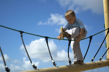 Boy climbing and playing against a blue background.の写真素材