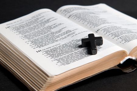 Closeup of Dutch Bible with cross, on black background.