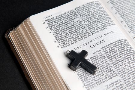 Closeup of Dutch Bible with cross, on black background.の写真素材