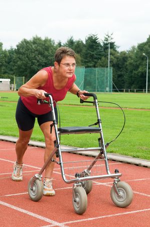 Disabled athlete at the starting line with her walker. Caricature picture to illustrate disability, ability, getting older, not wanna quit.の写真素材
