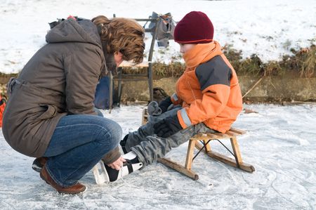Mother helping her son putting on his iceskates