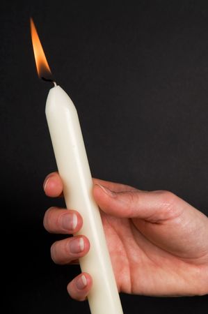 Woman's hand holding a candle, against black background. の写真素材
