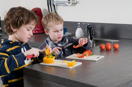 Two boys cutting some red and yellow peppers, used for cooking.の写真素材