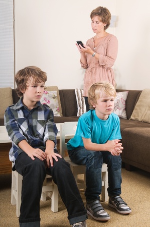 Children are watching tv while mother is calling in the backgroundの写真素材