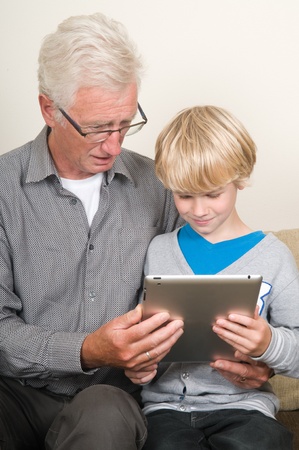 This kid learns his grandpa to use a tablet pcの写真素材