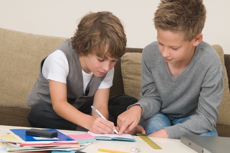 Two friends doing their homework in the livingroomの写真素材