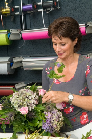 Female florist working in a flower store, making the bouquet ready for the customerの写真素材