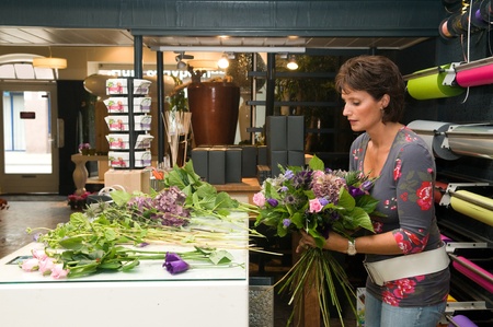 Female florist working in a flower store, making the bouquet ready for the customerの写真素材
