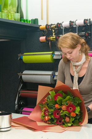 Female florist working in a flower store, making the bouquet ready for the customerの写真素材