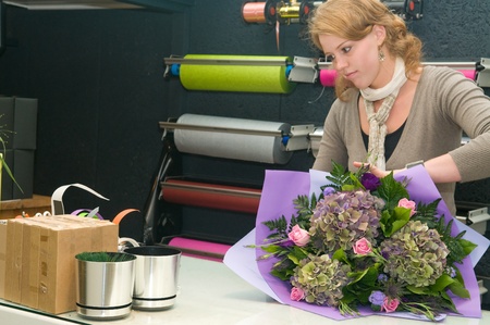 Female florist working in a flower store, making the bouquet ready for the customerの写真素材