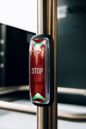 Bus stop request button with indicator lighting and raised tactile markings for accessibility.