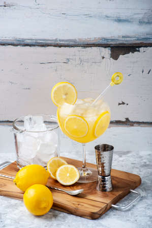 Limoncello and gin cocktail on a kitchen board, ice bucket, whole and sliced ââlemons and gin dispenser. Copy space.の写真素材