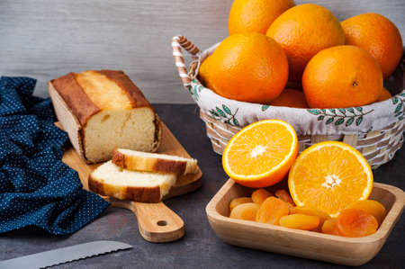 table with whole and sliced ââoranges, dried apricot and orange cake on a kitchen board ..の写真素材