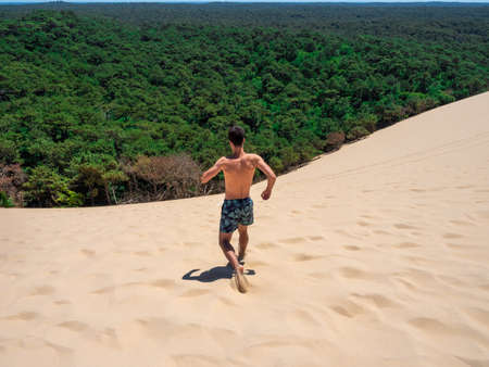Young caucasian man walking on the sand in Dune of Pilat in Arcachon France