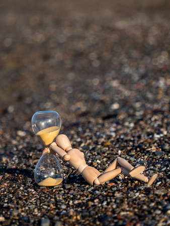 Human Wooden stick figure next to hourglass on the beach at the seashoreの写真素材