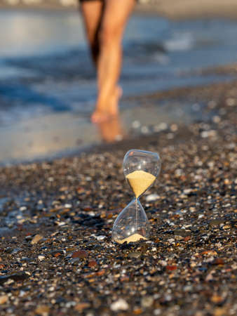 Person walking near Hourglass on the beach at the seashoreの写真素材
